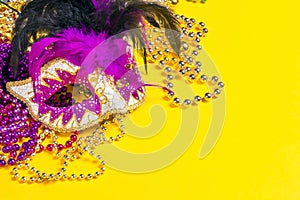 Festive Carnival mask and beads on yellow background