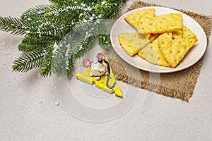 Festive cheese crackers, New Year snack concept. Cookies, mouse figure, fir tree branch, artificial snow, sackcloth napkin. Stone