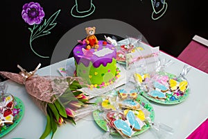 Festive children`s table with a beautiful bear cake flowers and colorful cookies. CandyBar. Children`s Day Births