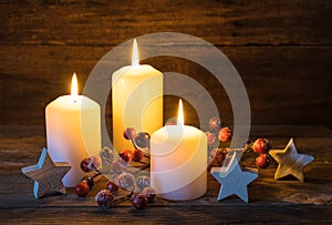 Festive Christmas background with burning candles, stars and red berries decoration.