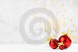 Festive christmas background with two champagne glasses, bright christmas decoration - red balls, golden ribbons, hang curling.
