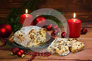 festive christmas cake, german criststollen with raisins and almonds, decorated with burning candles, red christmas balls and fir