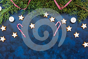 Festive Christmas composition, conifer, candy canes, candles and cookies on bleu vintage background. Christmas, winter