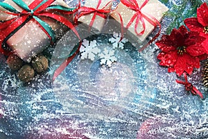 Festive Christmas composition with gifts, boxes, cones, walnuts, red flowers of poinsettia on a wooden background with white sprin