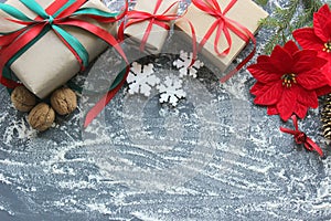 Festive Christmas composition with gifts, boxes, cones, walnuts, red flowers of poinsettia on a wooden background with white sprin