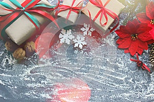 Festive Christmas composition with gifts, boxes, cones, walnuts, red flowers of poinsettia on a wooden background with white sprin