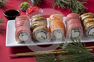 Festive Christmas dinner with salmon, tuna and eel sushi set with philadelphia cheese on white plate on red background