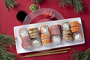 Festive Christmas dinner with salmon, tuna and eel sushi set with philadelphia cheese on white plate on red background