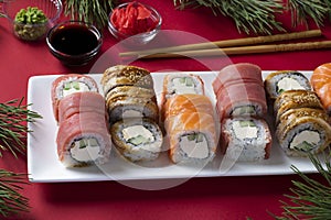 Festive Christmas dinner with salmon, tuna and eel sushi set with philadelphia cheese on white plate on red background