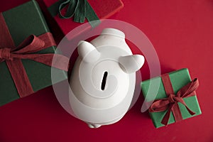 Festive Christmas financial savings concept. White piggy bank money box with presents