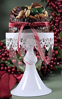 Festive Christmas food, fruit cake with glace cherries and nuts on white cake stand - vertical