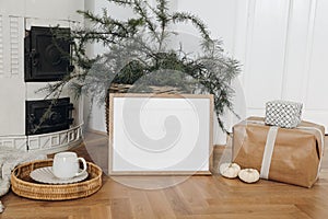 Festive Christmas home decor. Landscape wooden picture frame mockup on parquette floor. Pine, larch tree branches in