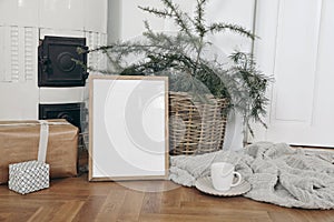 Festive Christmas indoor decor. Vertical wooden picture frame mockup on parquette floor. Pine, larch tree branches in