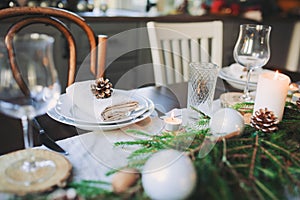 Festive Christmas and New Year table setting in scandinavian style with rustic handmade details in natural and white tones