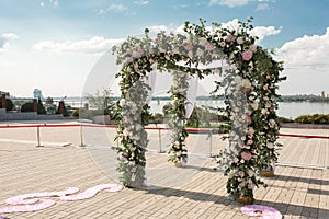 A festive chuppah decorated with fresh beautiful flowers for an outdoor wedding ceremony