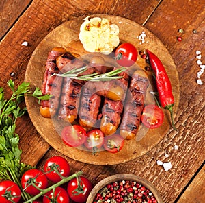 Festive cocktail sausages wrapped in crispy smoked bacon commonly known as `Pigs in Blankets` on wooden background