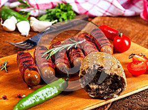 Festive cocktail sausages wrapped in crispy smoked bacon commonly known as `Pigs in Blankets` on wooden background