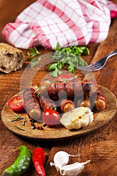 Festive cocktail sausages wrapped in crispy smoked bacon commonly known as `Pigs in Blankets` on wooden background