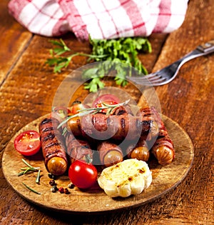 Festive cocktail sausages wrapped in crispy smoked bacon commonly known as `Pigs in Blankets` on wooden background