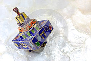 Festive colorful enameled Hanukkah dreidel on a soft white background photo