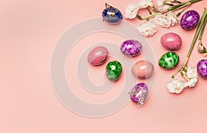 Festive composition, colorful Easter eggs and daffodils on a pink background, place for the text