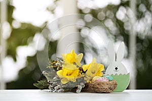 Festive composition with Easter eggs in decorative nest on table against window