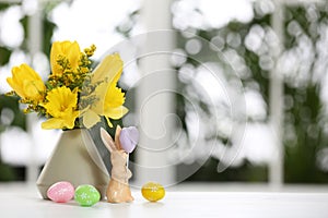 Festive composition with Easter eggs on table against window, space for text