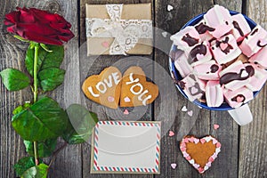 Festive composition with homemade cookies in shape of heart with Love you lettering, greeting card, rose, gift box and cup of caca