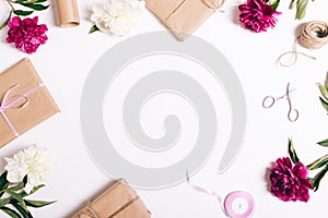 Festive composition of peonies and gifts on a white table