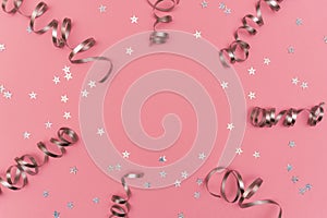 Festive composition with silver confetti and serpentine on pink background. Celebration concept ideas for Christmas, New Year or