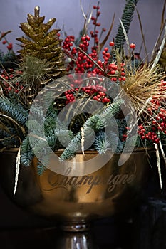 Festive composition of twigs of natural blue spruce tree, ilex verticillata winterberries, decorated with golden cones and leaves