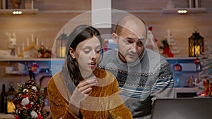 Festive couple doing christmas shopping online with credit card