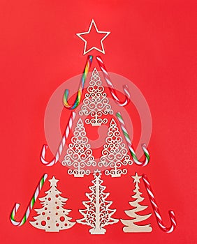 Festive creative Christmas tree of carved wooden decorations and traditional xmas candy canes on red background
