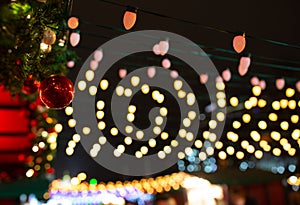 Festive dark blurred background with bokeh lights, electric garland. Garlands of lamps on a wooden stand on the street.