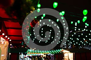 Festive dark blurred background with bokeh lights, electric garland. Garlands of lamps on a wooden stand on the street.