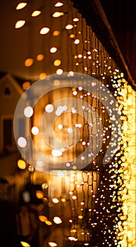 Festive dark blurred background with bokeh lights, garland and house