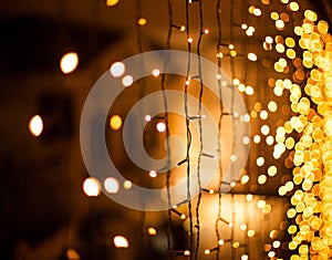 Festive dark blurred background with bokeh lights, garland and house