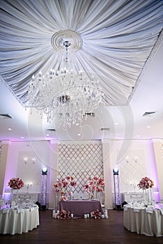 festive decor in restaurant for a wedding, decoration of the hall with large flowers, unusual fabric ceiling