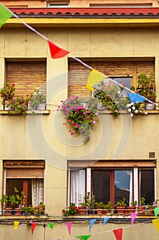 Festive decorated facade of an old European house with flowers and colorful flags