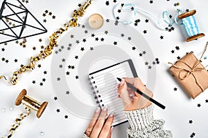 Festive decorations, delicate wavy ribbons, metallic star shaped confetti and notebook with wish list on white table