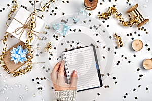 Festive decorations, delicate wavy ribbons, metallic star shaped confetti and notebook with wish list on white table