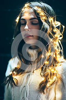 Festive dreaming woman portrait with christmas lights and closed