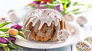 Festive easter marble cake with icing sugar hand-decorated eggs and spring tulips