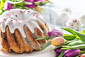 Festive easter marble cake with icing sugar hand-decorated eggs and spring tulips