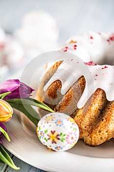 Festive easter marble cake with icing sugar hand-decorated eggs and spring tulips