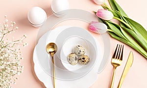 Festive Easter table decoration idea with eggs, spring flowers, golden cutlery, beautiful plates.
