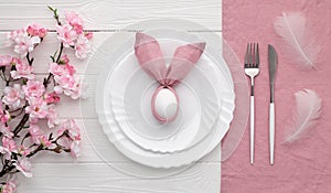 Festive Easter table setting with bunny made of pink linen napkin and egg. Top view. Happy Easter holiday concept for restaurant