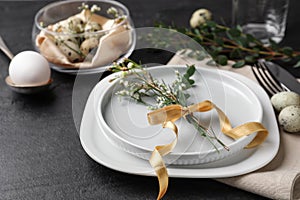 Festive Easter table setting with eggs and floral decoration on dark background, closeup
