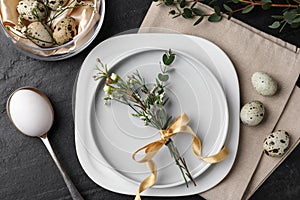 Festive Easter table setting with eggs and floral decoration on dark background, flat lay