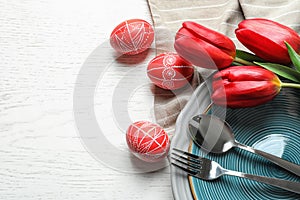 Festive Easter table setting with flowers on wooden background, top view.